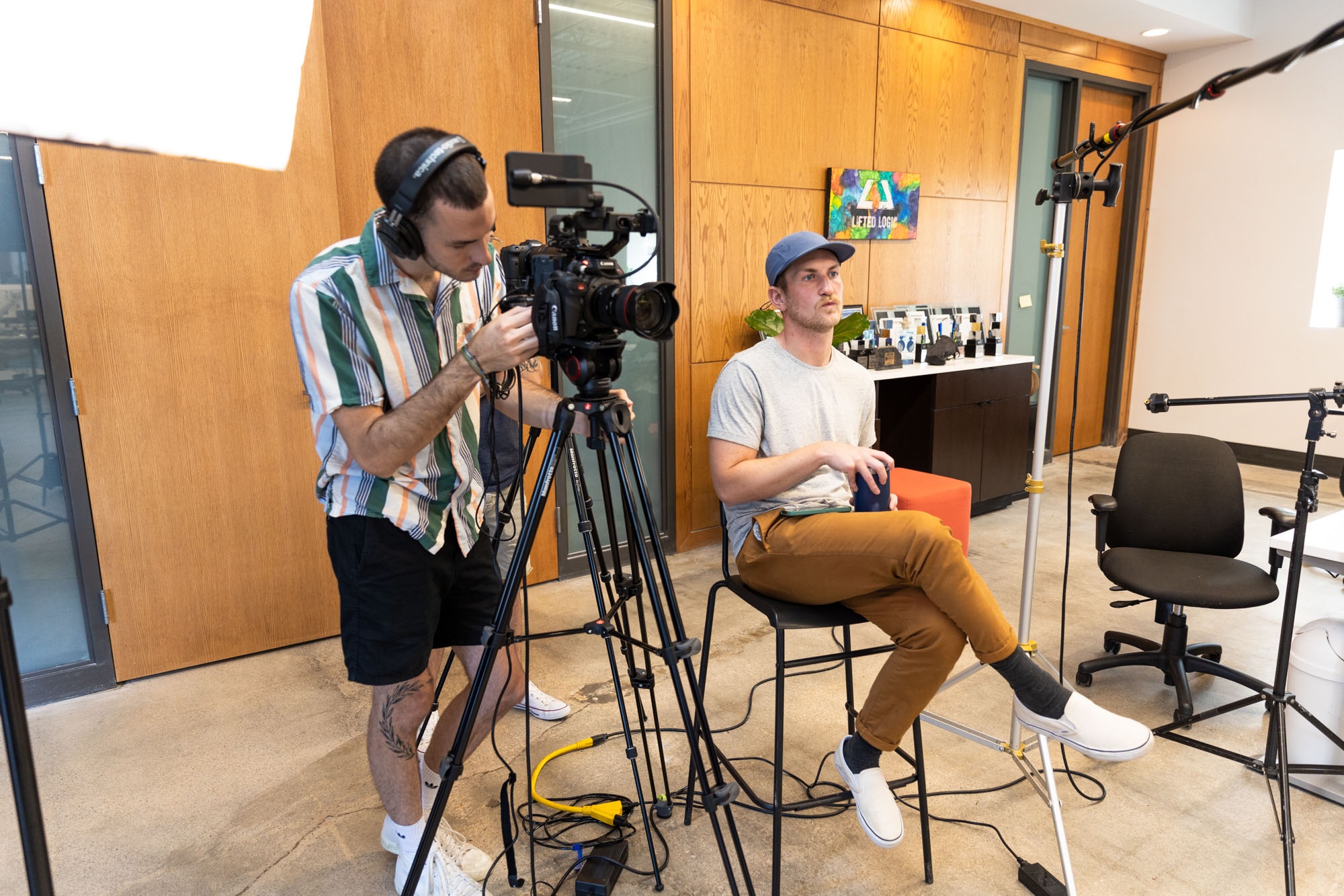 Lifted Logic offers HD video production in Kansas City. Here, a videographer is filming an indoor interview using professional lighting, audio, and camera equipment.