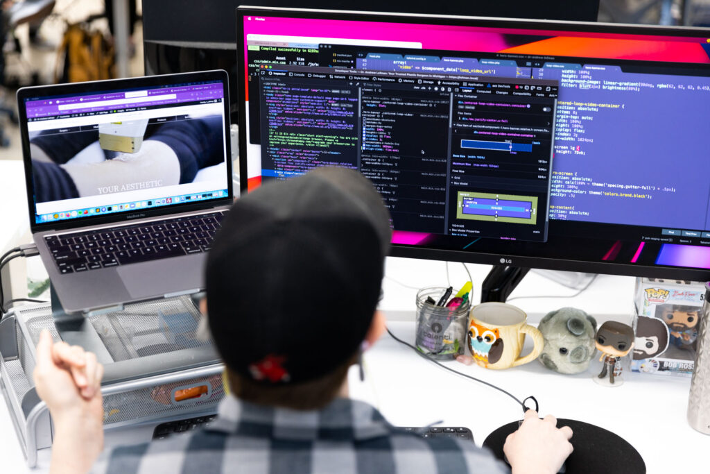 Our team offers services for e-commerce web development in Kansas City. An employee sits in front of 2 monitors working on an e-commerce website.