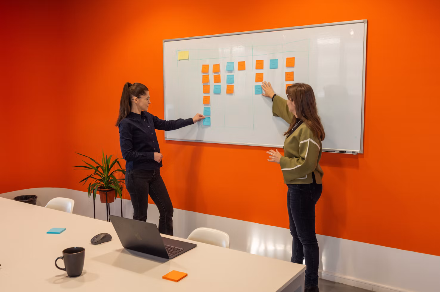 Two marketing team members standing in front of a white board discussing contrasting strategies.