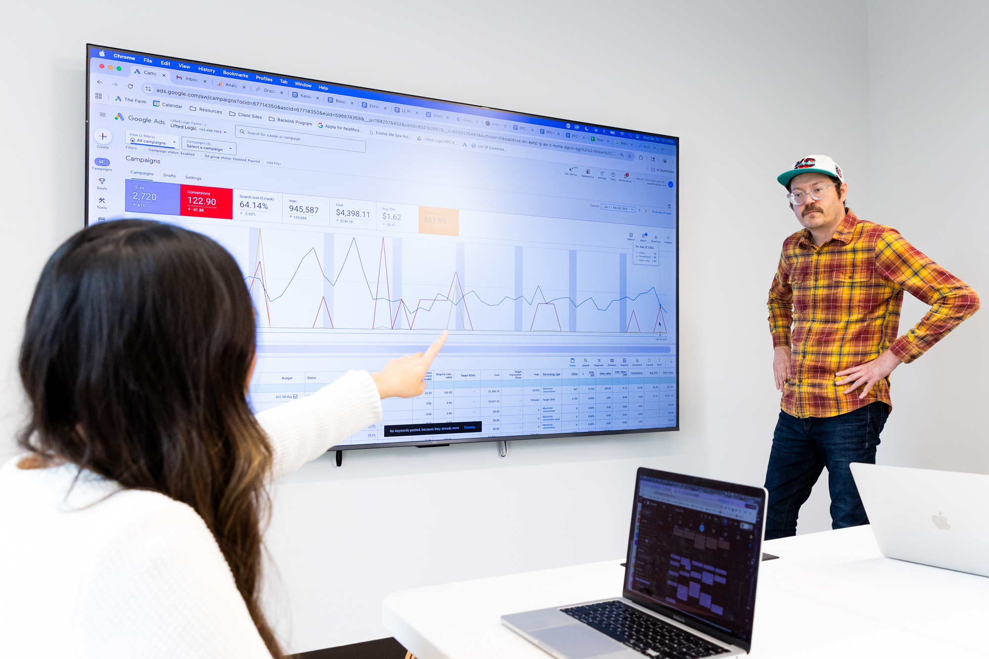 Members of the Lifted Logic team discuss metrics displayed on a screen, highlighting the value of organic SEO and paid search for Kansas City businesses.