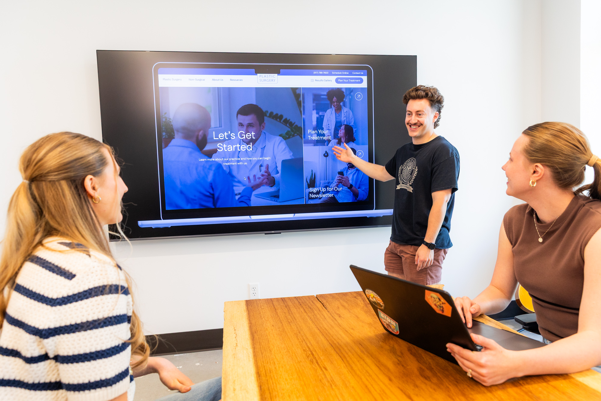 Members of the Lifted Logic team discuss a Kansas City client's new website, using a mockup on the screen to display the various components and SEO content pieces.